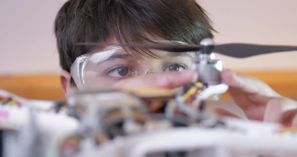 A Boy Wearing Goggles Installs a Propeller on a Disassembled Drone alt