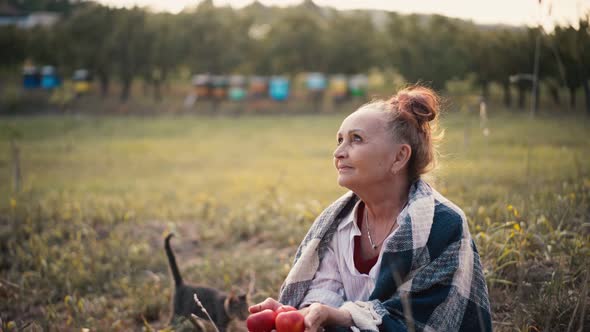 A Mature Adult Woman Dreamily Sits with Apples in Her Hands