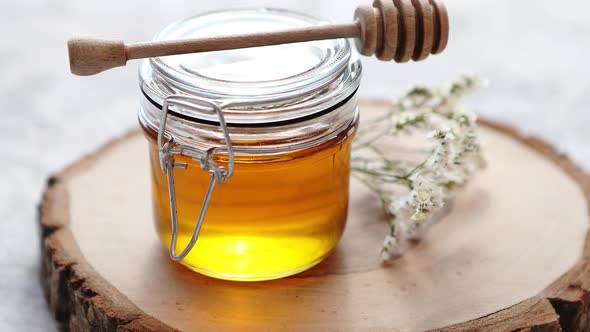 Glass Jar Full of Fresh Honey Placed on Slice of Wood alt