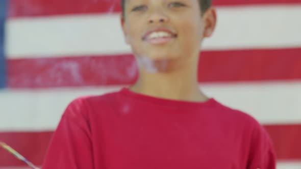 Boy with sparkler and flag on Fourth of July