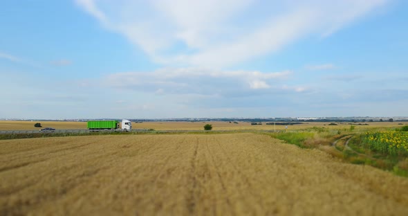 The Road Between The Wheat Field On Which Trucks Move