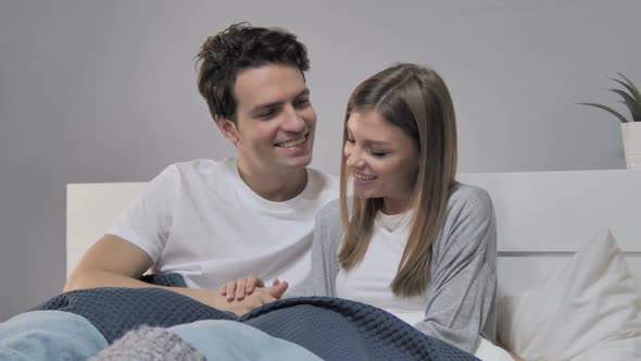 Young Couple Having Romantic Talk While Relaxing in Bed alt