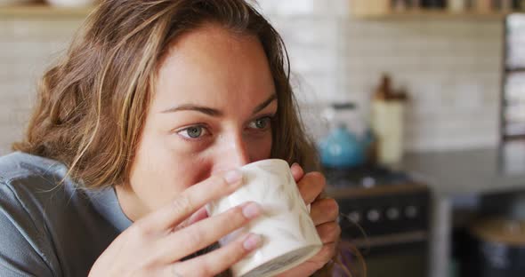 Thoughtful caucasian woman in sunny cottage kitchen drinking coffee alt
