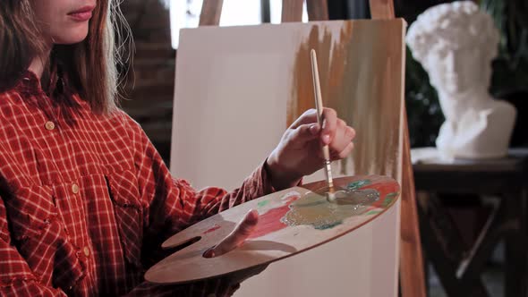 A Young Woman Artist Applying Base Colors on a Canvas with a Small Brush alt