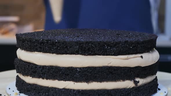The Pastry Chef Squeezes a Thick Layer of Cream Onto a Multilayered Sponge Cake