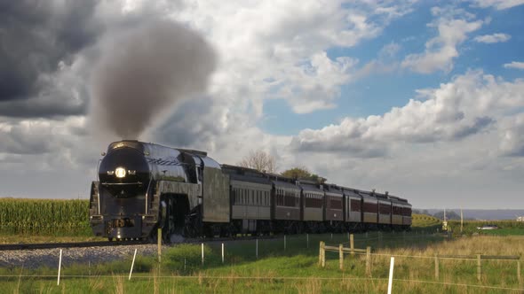 View of an Antique Steam Passenger Train Blowing Smoke and Steam Traveling Thru Fertile Corn Fields alt