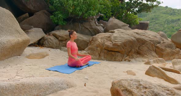 Woman Practicing Yoga in the Morning She Seats on the Beach on Yoga Mat and Meditating alt