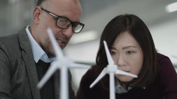 Business people examining wind turbine models in office