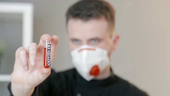 Close-up of a Test Tube with a Blood Test of Coronavirus in the Doctor's Hand. The Doctor's Face  alt