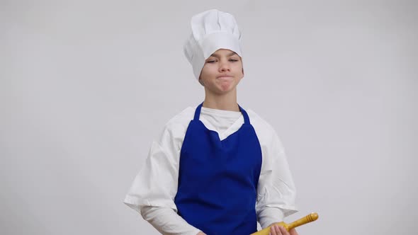 Dissatisfied Little Chef in Uniform Threatening with Rolling Pin Posing at White Background alt