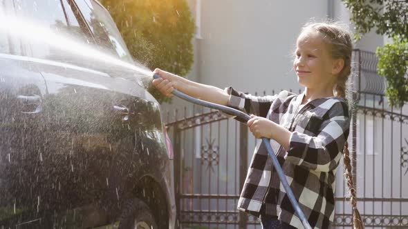 Girl Rinses the Car Water From a Hose