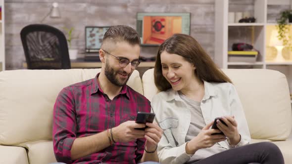 Couple Laughing Together While Browsing on Their Phones alt