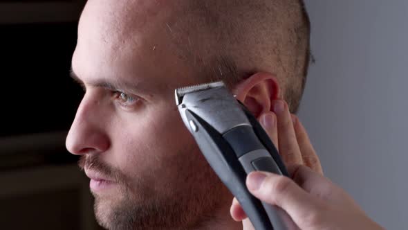 Hairdresser Shaves a Man Hair with a Hair Clipper. alt