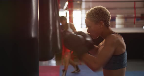 Mixed race women boxing in punchbag alt