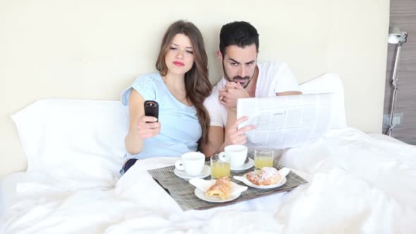 Young Couple Watching TV on the Bed