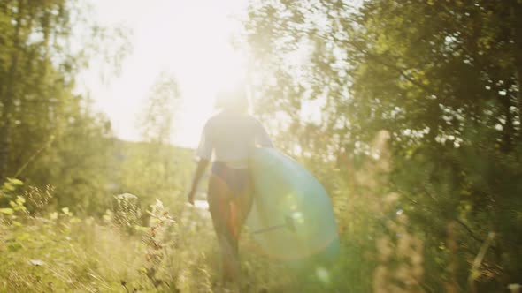 Woman Carrying Surfing Board to Lake or River in Sunlight alt