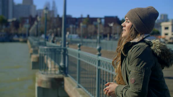 thoughtful young woman looks across water from pier and considers future alt