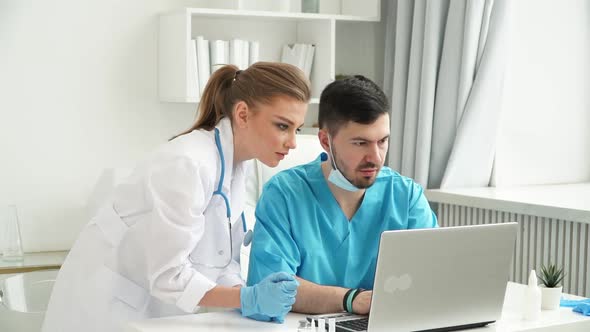 Team of Doctors Work at Computer and Discuss Patients Diagnosis at Laptop in Clinic alt