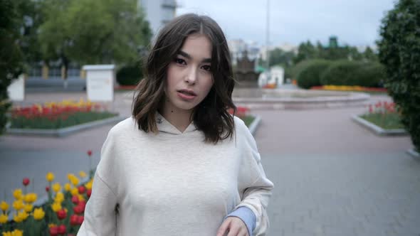 Young Girl Walking Against the Backdrop of a City Park, Alone alt