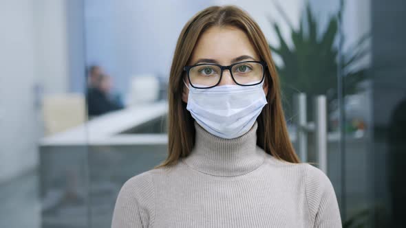 Portrait of a Woman in Glasses and a Protective Mask Looking Into the Camera Office Worker alt