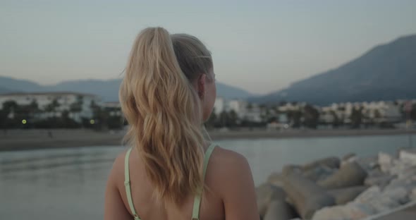 Woman Walking In Sunset Along Promenade By Sea alt
