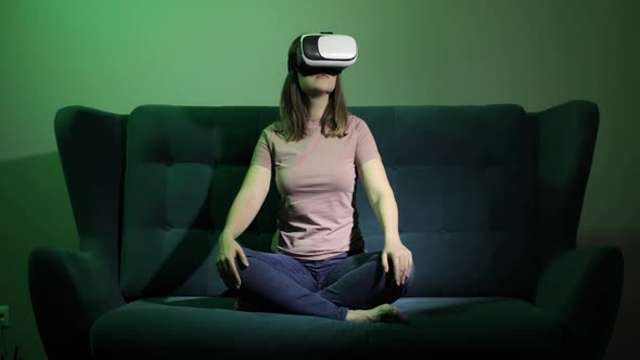 Woman Is Sitting on Sofa in Virtual Reality Glasses and Touching Hands in Air