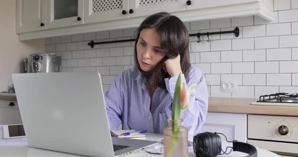 Focused European woman distance working online on laptop communicate with clients by webcam alt