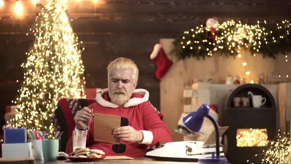 Santa Claus Sitting at Home and Writing on Paper To Do List with Quill Pen and Ink at Night alt