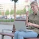 Distressed Woman with Headache Using Laptop while Sitting Outdoor on Bench