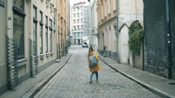 Female Tourist Is Walking Along a Narrow Street with a Map alt