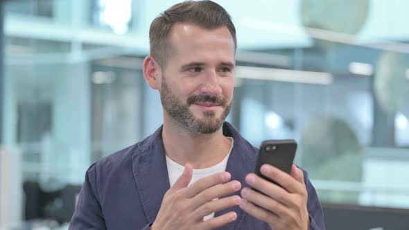 Middle Aged Businessman Celebrating on Smartphone alt