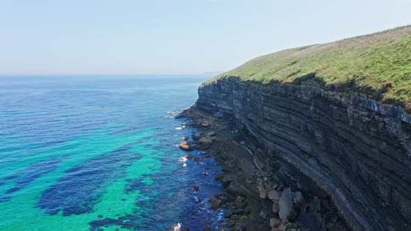 Large rocky cliffs stratified on turquoise sea water shore of northern Spain alt