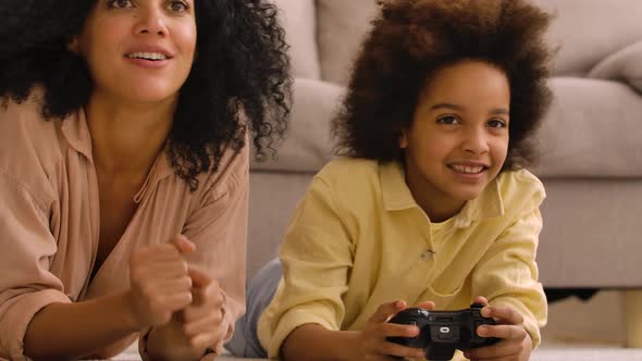 Little African American Girl Plays Game on Wireless Joystick and Rejoices Victory alt