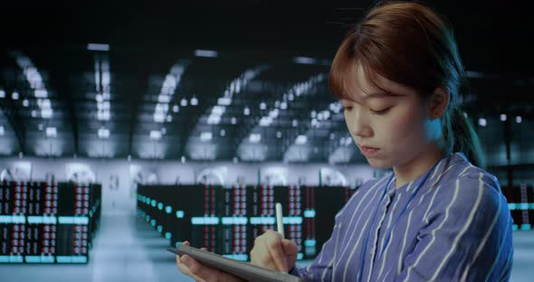 A Young Female Using Tablet While Working in Server Room in Contemporary Data Center