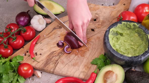Making Guacamole Sauce  Woman Chopping Red Mars Onion on a Wooden Cutting Board alt