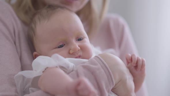 Closeup Cute Thoughtful Baby Girl in Hands of Unrecognizable Caucasian Woman alt