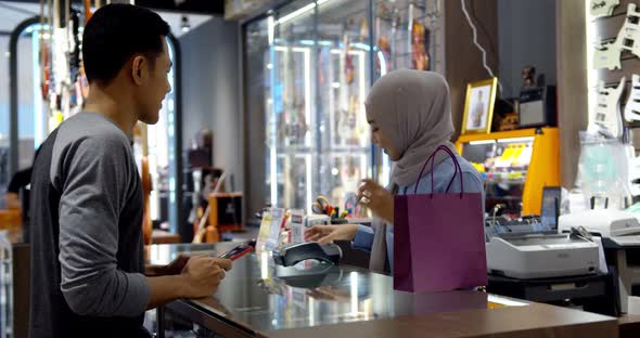 Young muslim man use smartphone paying over contactless transaction machine alt