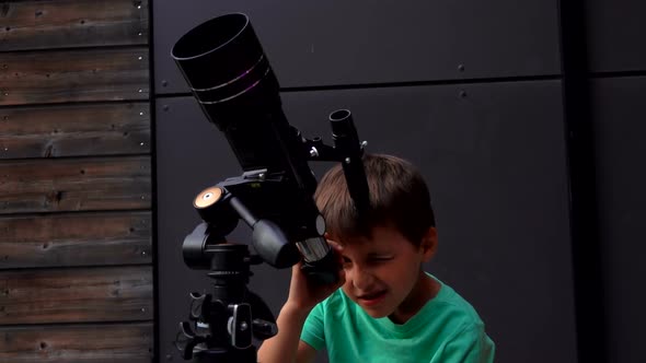 Little Tanned Boy is Setting Up a Telescope on a Summer Day to Look at the Sky alt