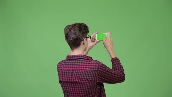 Young Handsome Teenage Nerd Boy Photographing with Phone alt