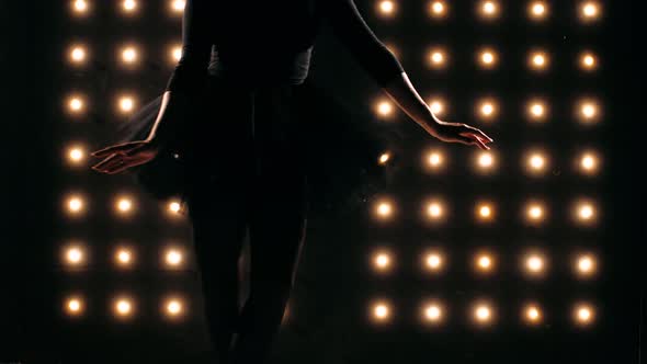 Silhouette of Ballerina in Black Dress is Dancing Ballet in the Dark Studio