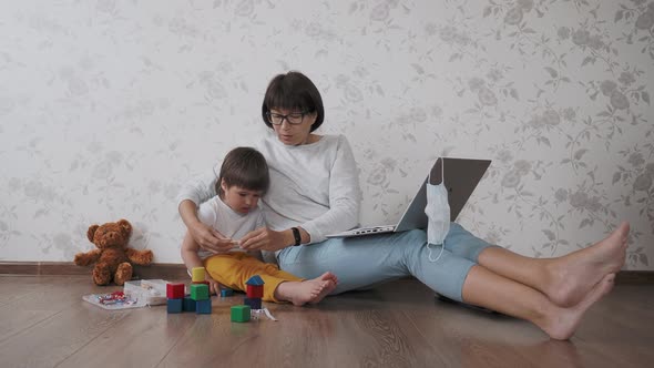 Mom and Son Sit at Home Quarantine Because of Coronavirus COVID19. Mother Remote Works with Laptop alt