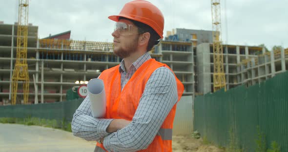 Portrait of an Architect or Builder in Hard Hat Standing in Front of Building Under Construction alt