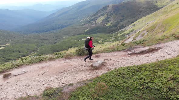 Aerial View of a Traveler Photographer with Backpack Climbing By Mountain Range alt