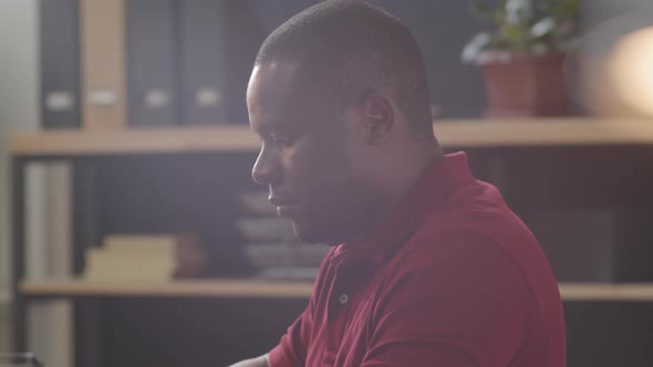 Black Man Typing on Laptop in Office alt