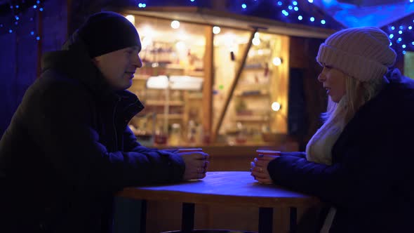 Happy Young Couple with Coffee at Christmas Market in Evening alt