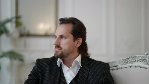 Handsome Man is Posing in Luxury Interior of Modern Palace Hall Dressed Classical Suit alt