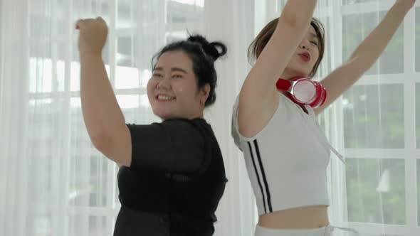 beautiful Asian woman and fat woman practicing dancing in the room cheerful and happy.