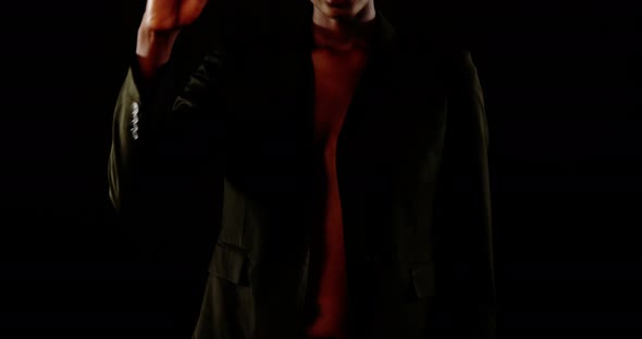 Androgynous man in blazer posing against black background alt