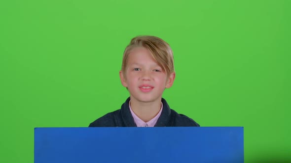 Child Boy in Jumper Emerges From Behind the Board and Waving on a Green Screen alt