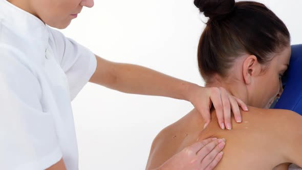 Profile view of therapist woman massaging the back of her patient alt